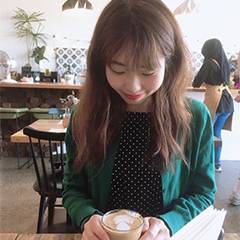 女性がコーヒーを持って下を向いて微笑んでいる