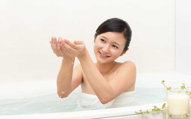 女性がお風呂でお湯を手ですくっている画像