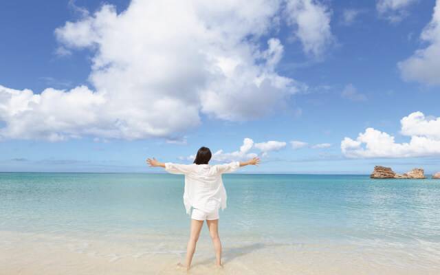 海で両手を広げてリラックスしている女性