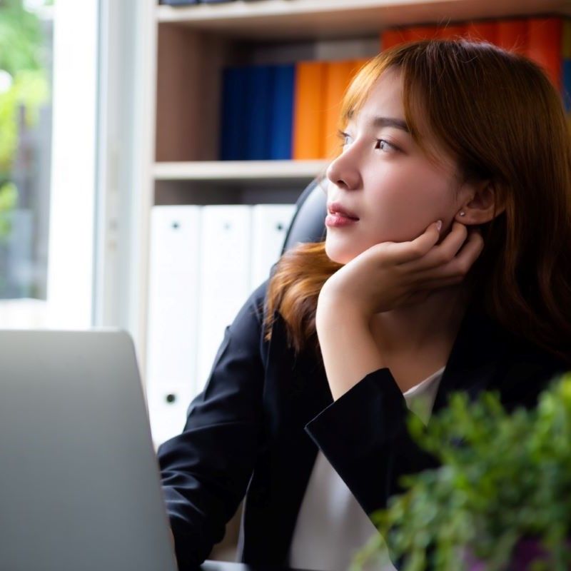 パソコン作業の途中でぼんやりと外を眺める女性