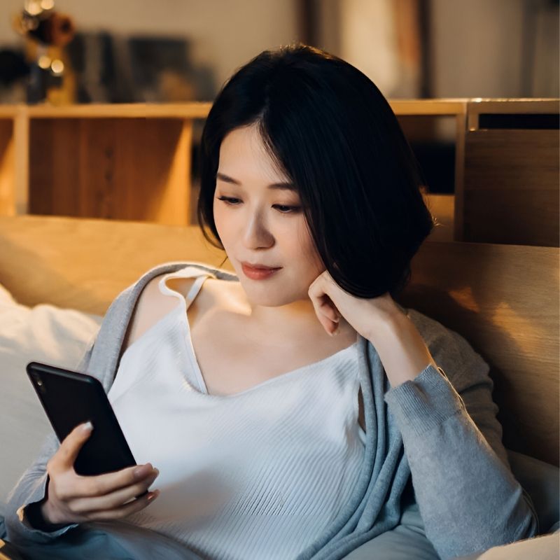 ベッドでスマホを見る女性