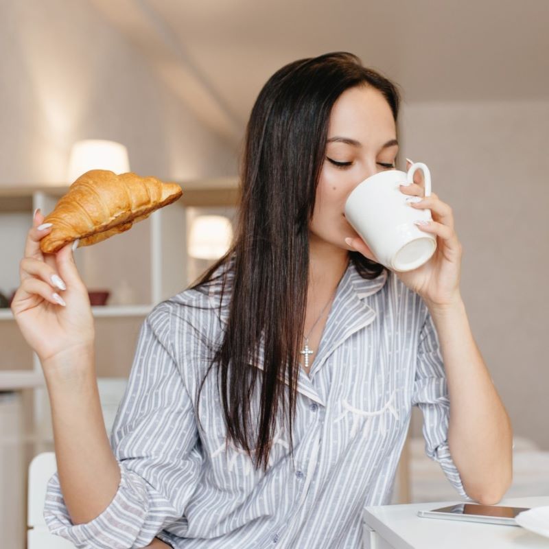 パンとコーヒーを食べる女性